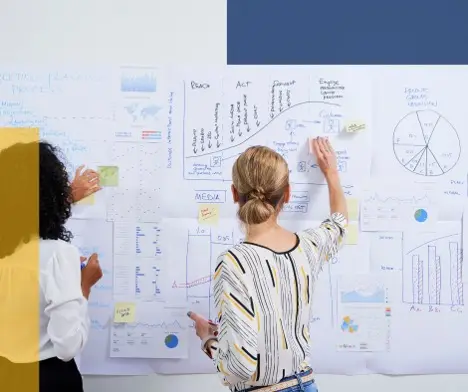 Two woman looking at a wall of data